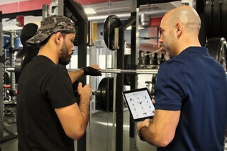 Therapist showing a tablet to a man training in a gym