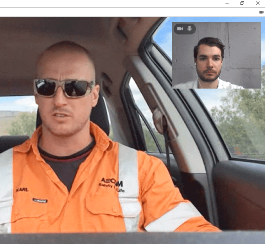Telehealth video call screenshot of a man in a hi-vis shirt sitting in a vehicle.