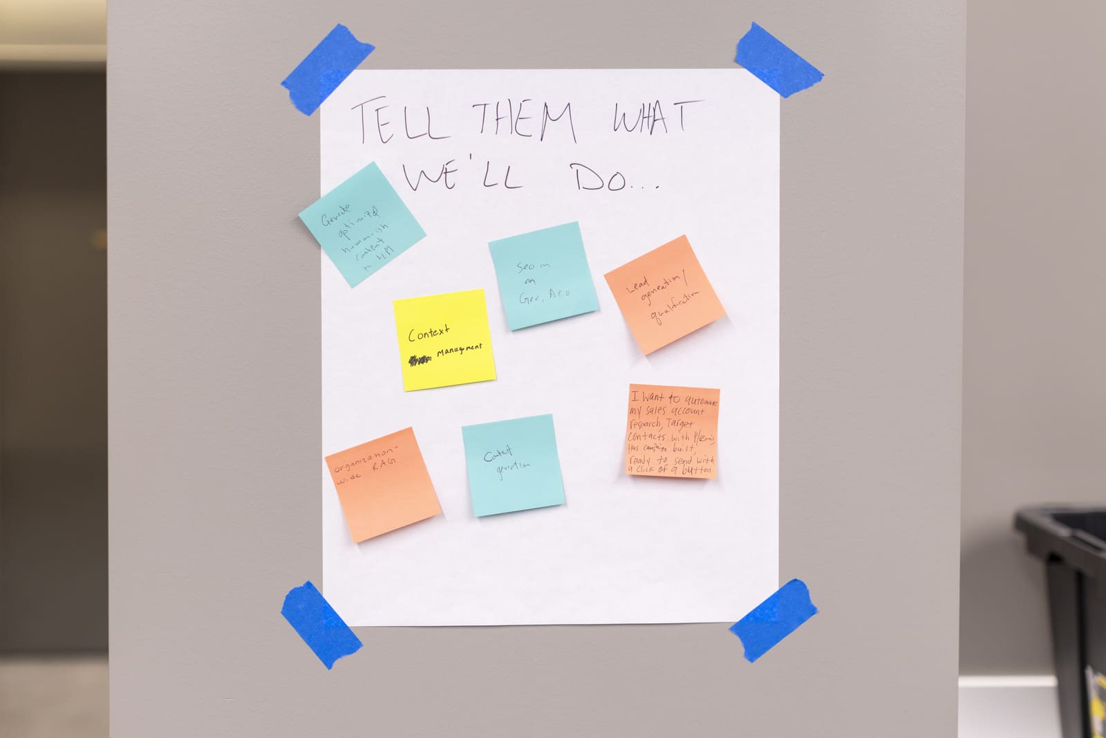 Workshop poster headed "Tell them what we will do" covered in sticky notes listing candidate AI use cases