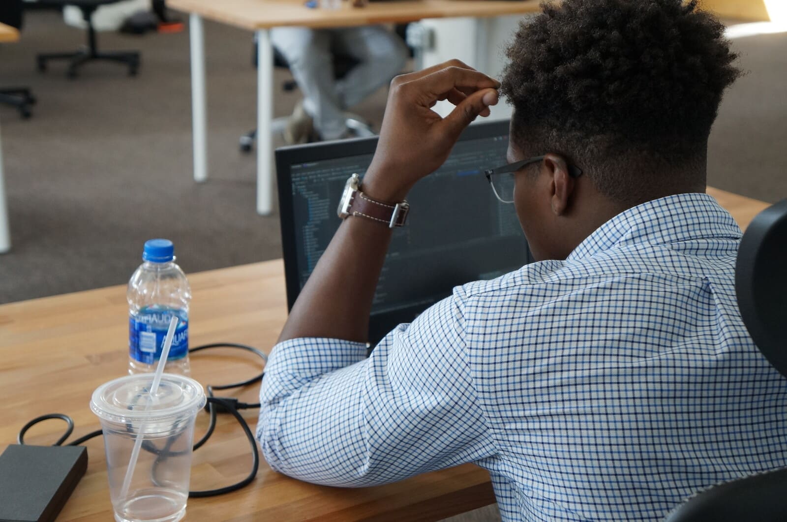 Developer leaning in to read a wall of source code on an external monitor