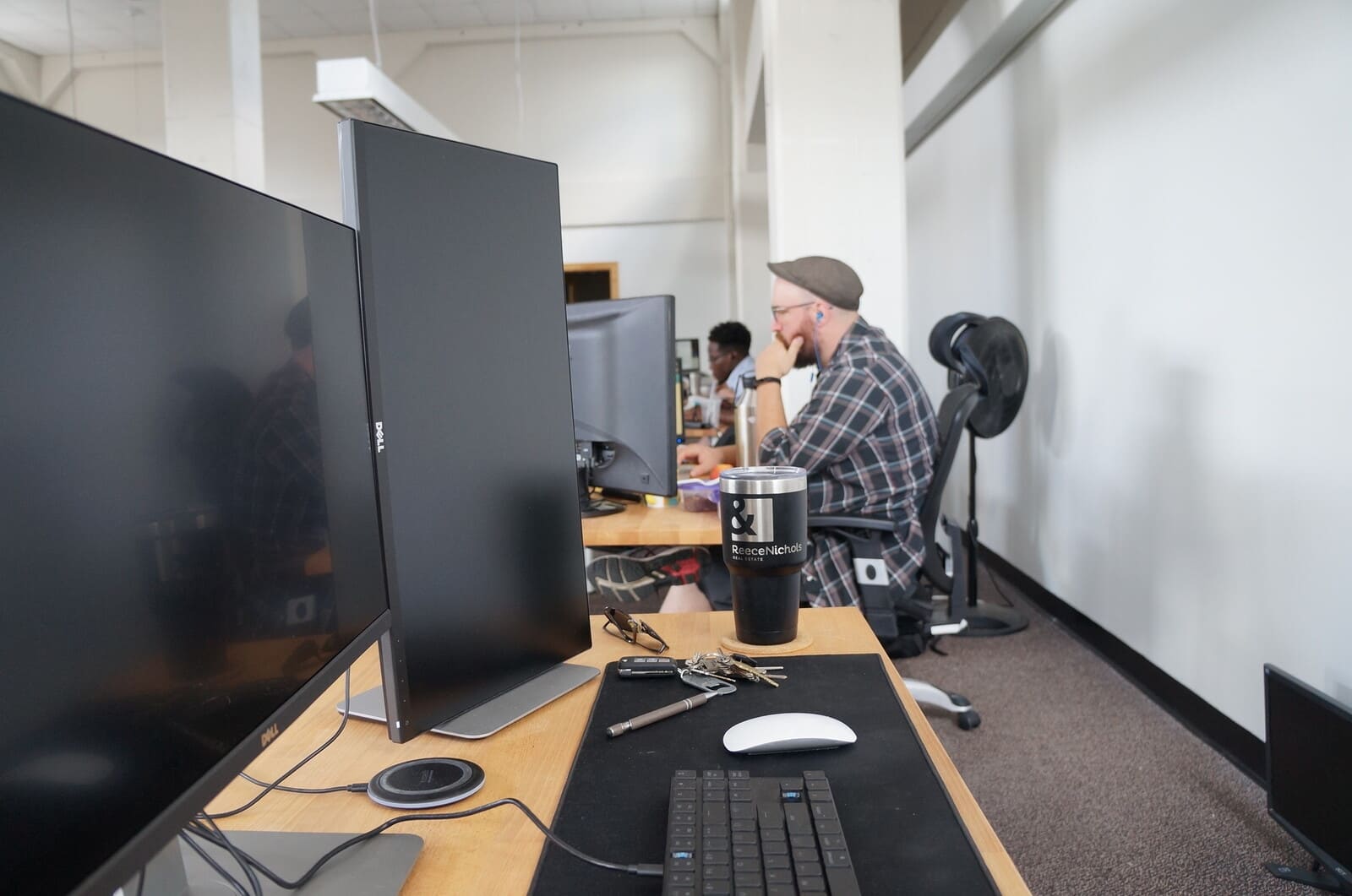 Open plan software development office with dual monitor desks and a developer at work