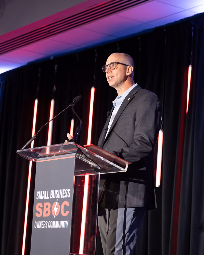 A male bike mechanic standing outside of his small business bike shop holding a bike.