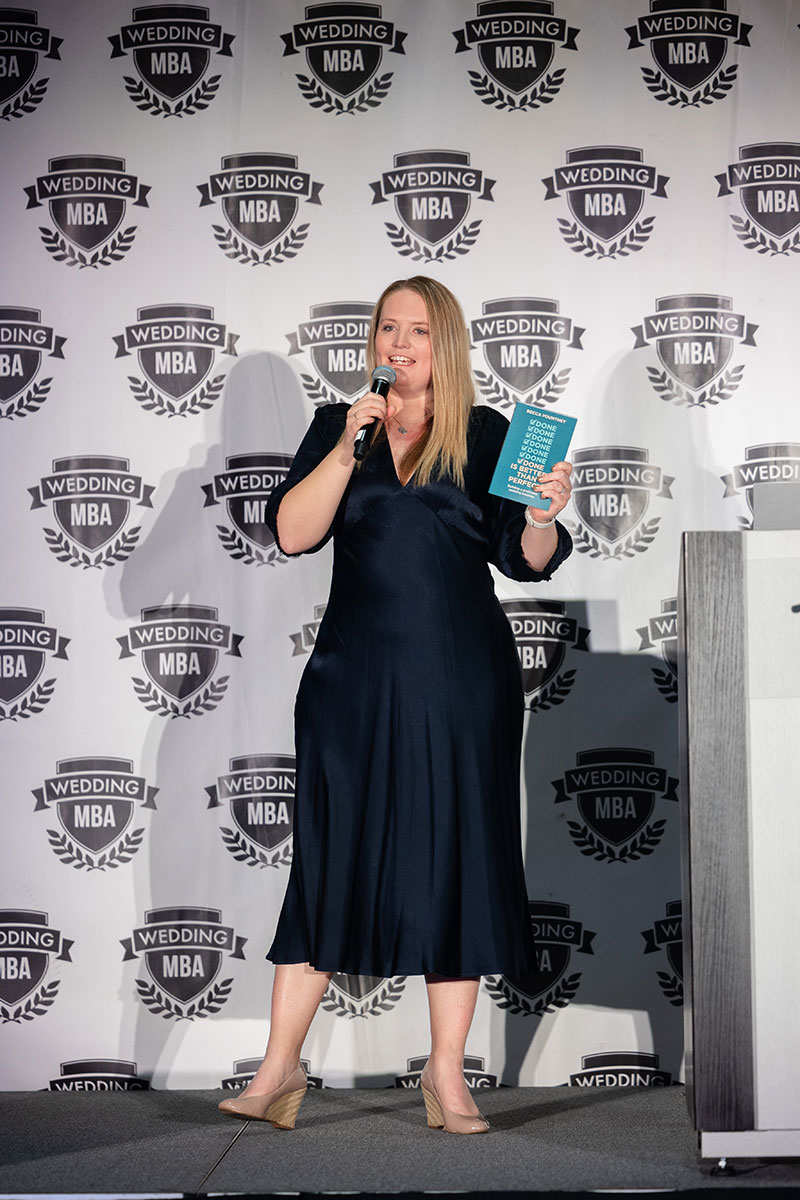 A male bike mechanic standing outside of his small business bike shop holding a bike.