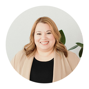 Headshot of a woman in a black top and tan sweater