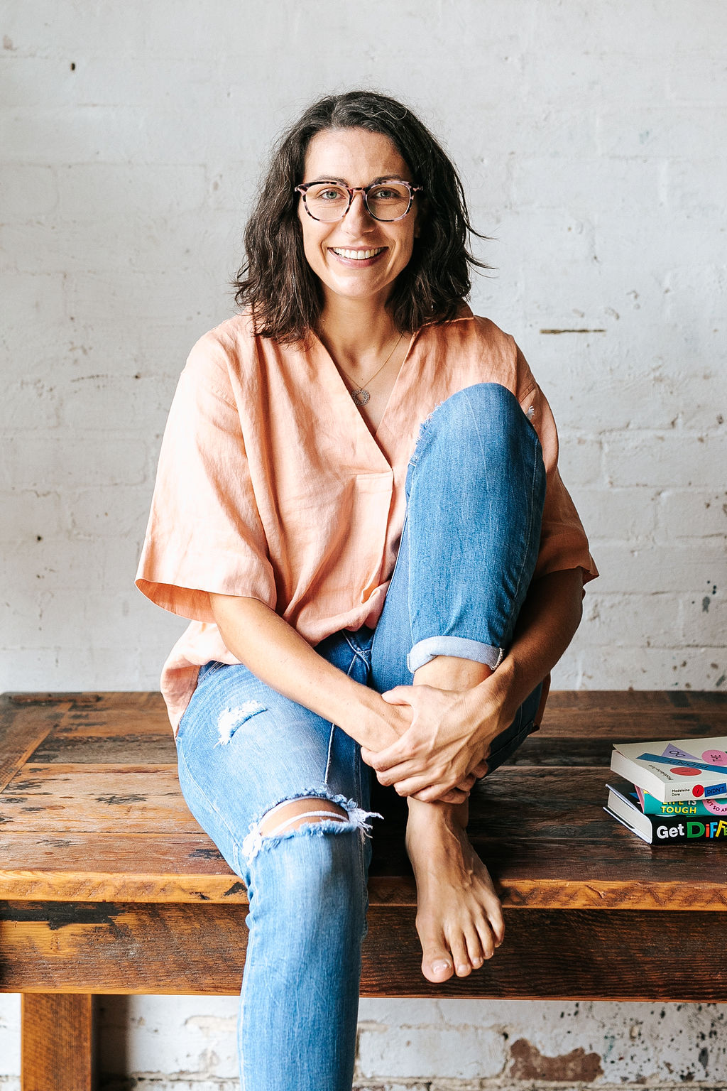 A woman with shoulder length brown hair wearing jeans and a pink shirt