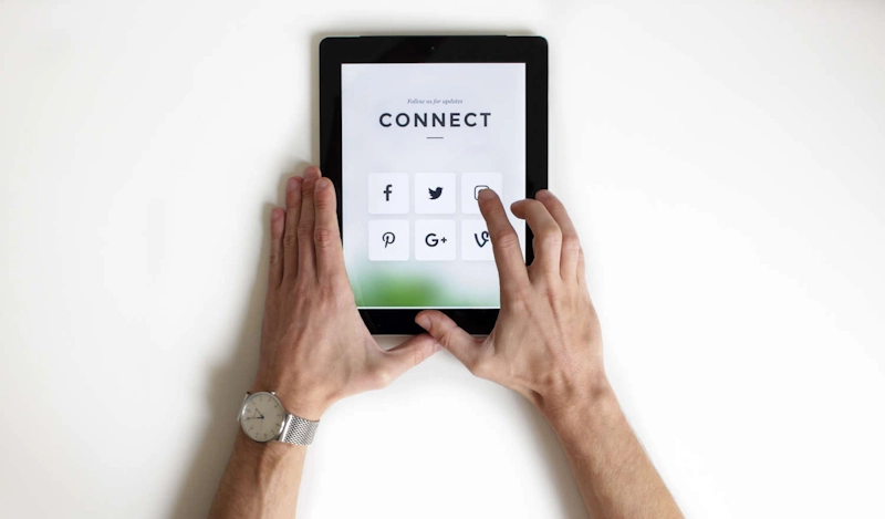 Close-up of a person using a tablet to connect on social media, illustrating integrated digital marketing and B2B PR services.