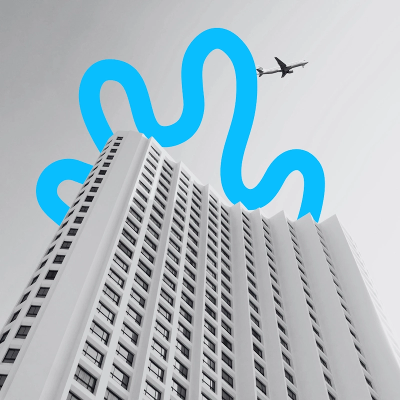Low-angle view of a high-rise hotel skyscraper with an airplane flying overhead, representing airport hotel marketing strategy.