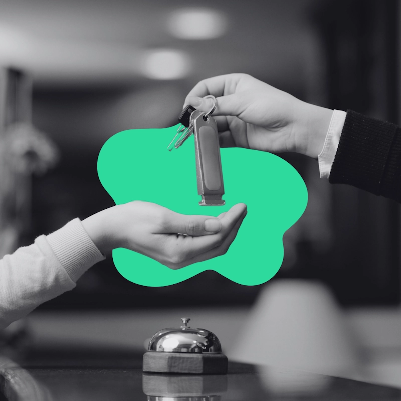 Hotel front desk staff handing room keys to a guest, representing increased hotel bookings and campaign conversion.