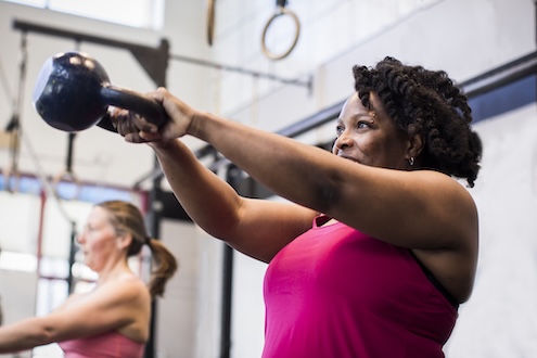 a woman swinging a kettlebell in a gym