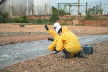 Two men testing the water near an industrial site