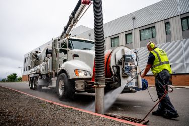 CatchAll Environmental worker pressure washing the drain 