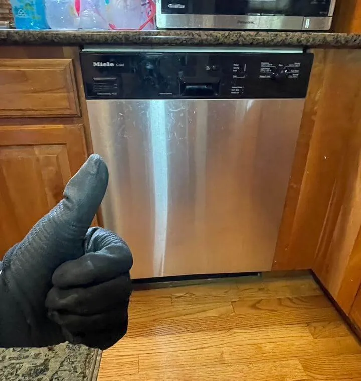 Stainless steel dishwasher with a thumbs-up from a technician – Professional dishwasher installation and repair.