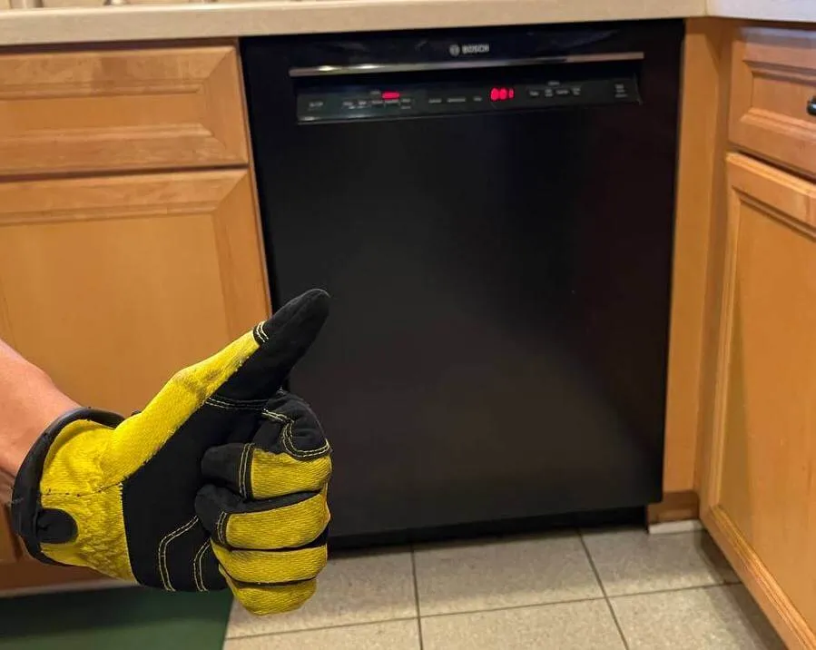 Black dishwasher in a wooden kitchen with a thumbs-up – Affordable dishwasher repair service.
