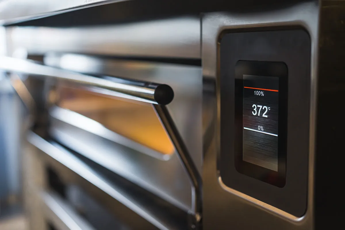 Close-up of a stainless steel oven with a digital display showing a temperature of 372°C at 100% power.