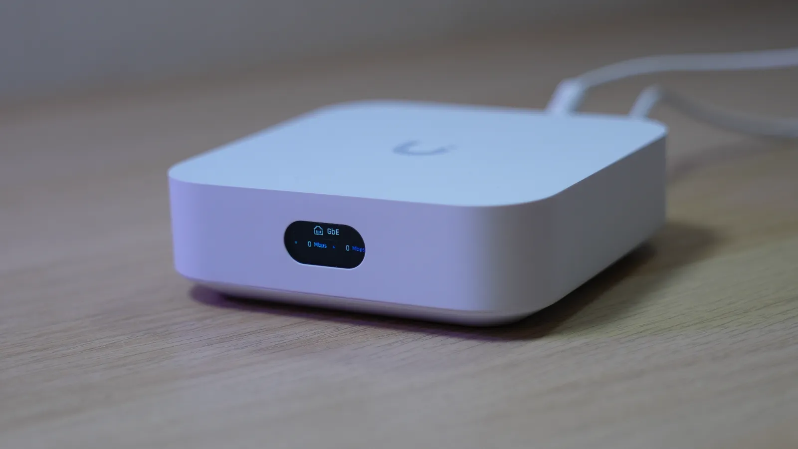 White UniFi Express with LCM screen on showing Mbps traffic and GbE wired ethernet status