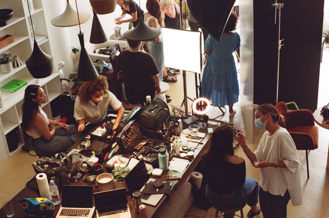 Film photo of a hair and makeup team preparing talent at a long table