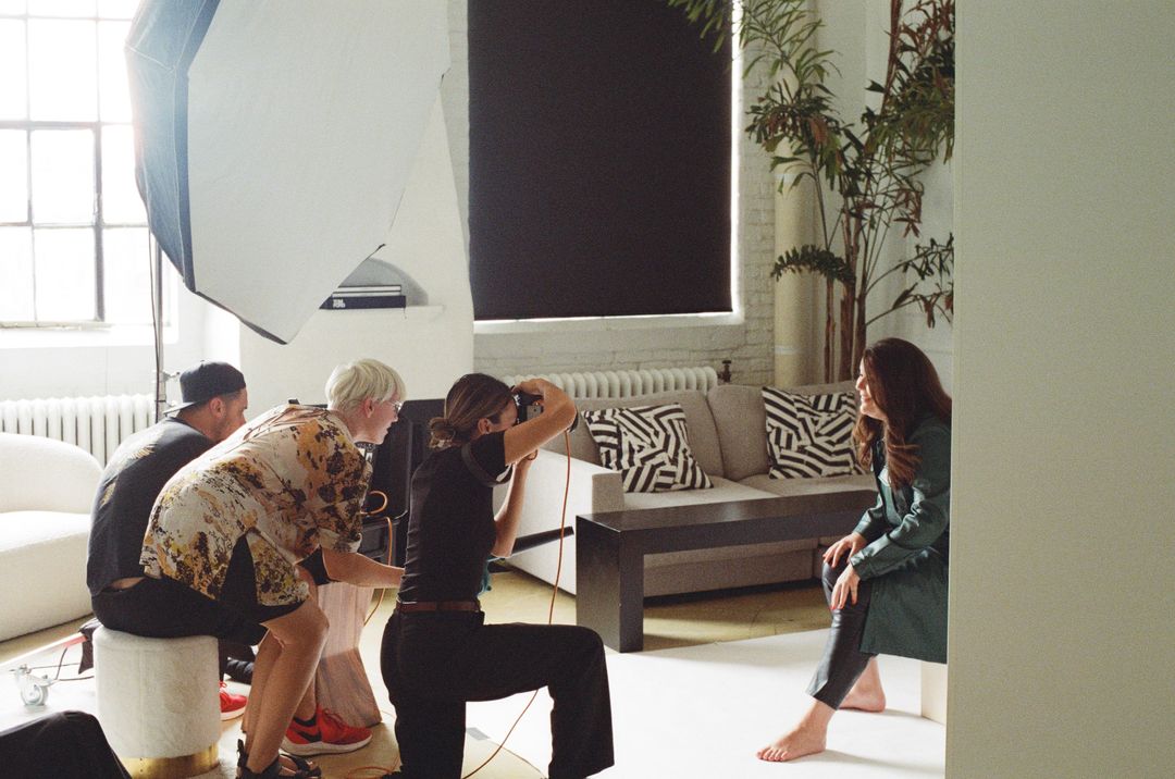 Film photo of a photographer shooting a model on a sofa beside a softbox