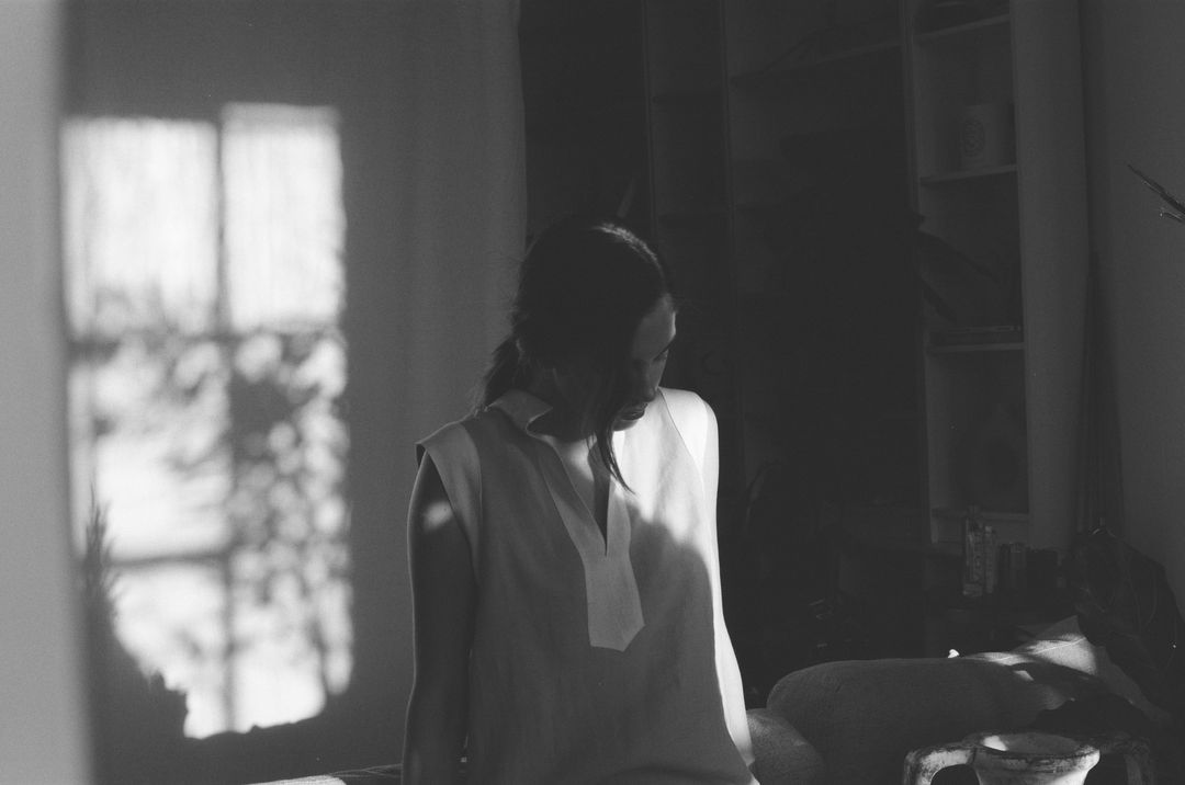 Black-and-white film portrait of a woman in window light and grid shadows