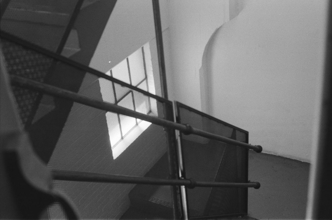 Black-and-white film photo of light falling across a stair railing