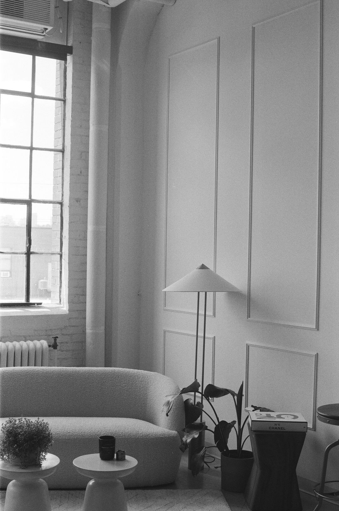 Black-and-white photo of a curved sofa beneath a tall window