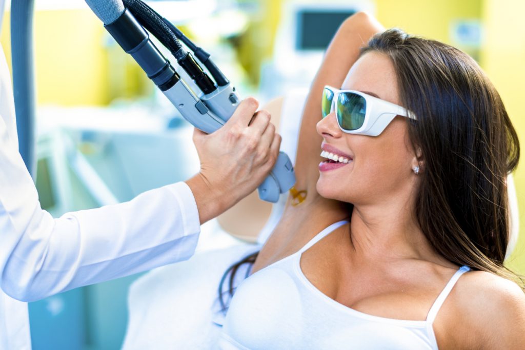 A woman getting her hair removed from armpit are by a laser treatment in a beauty salon