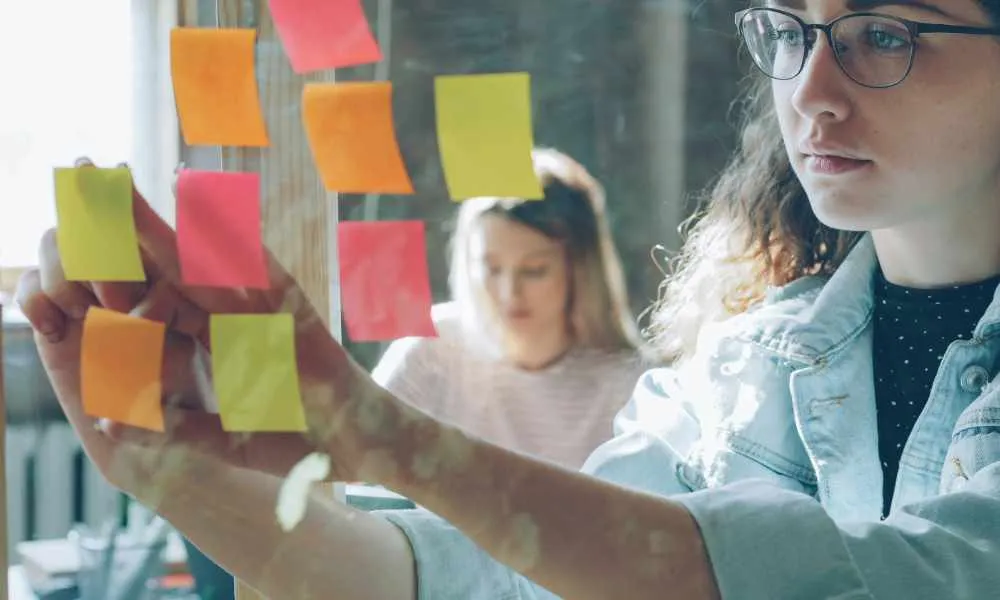 Twee werkende vrouwen met een raam waarop ze post-it's plakken