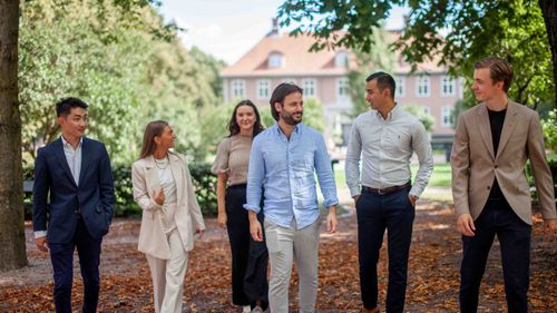 Gjeng med personer smiler og ler til hverandre mens de går fremover