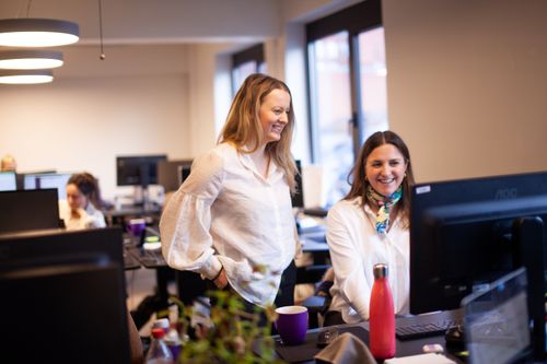 To damer som ser på en skjerm og smiler