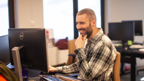 Smilende mann foran pc-skjerm