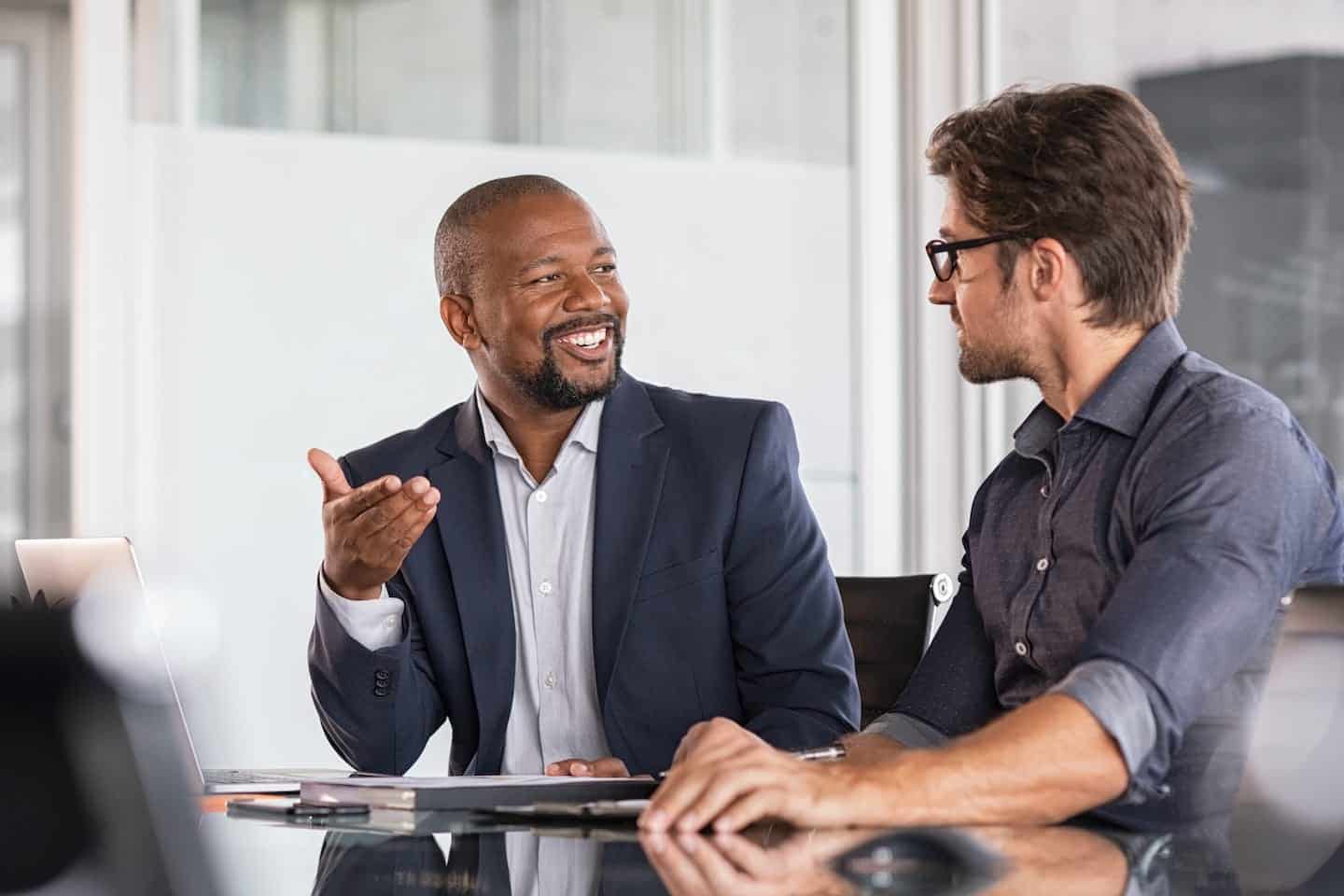 Photo of two men having a conversation at a conference table