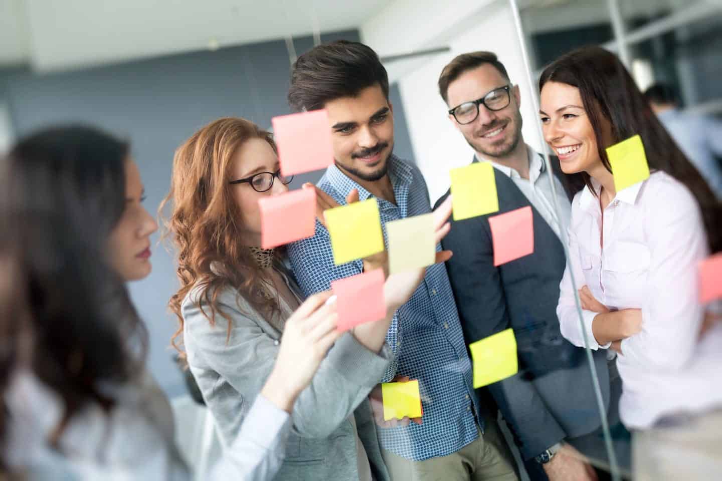 Photo of a team looking at sticky notes stuck to a glass wall
