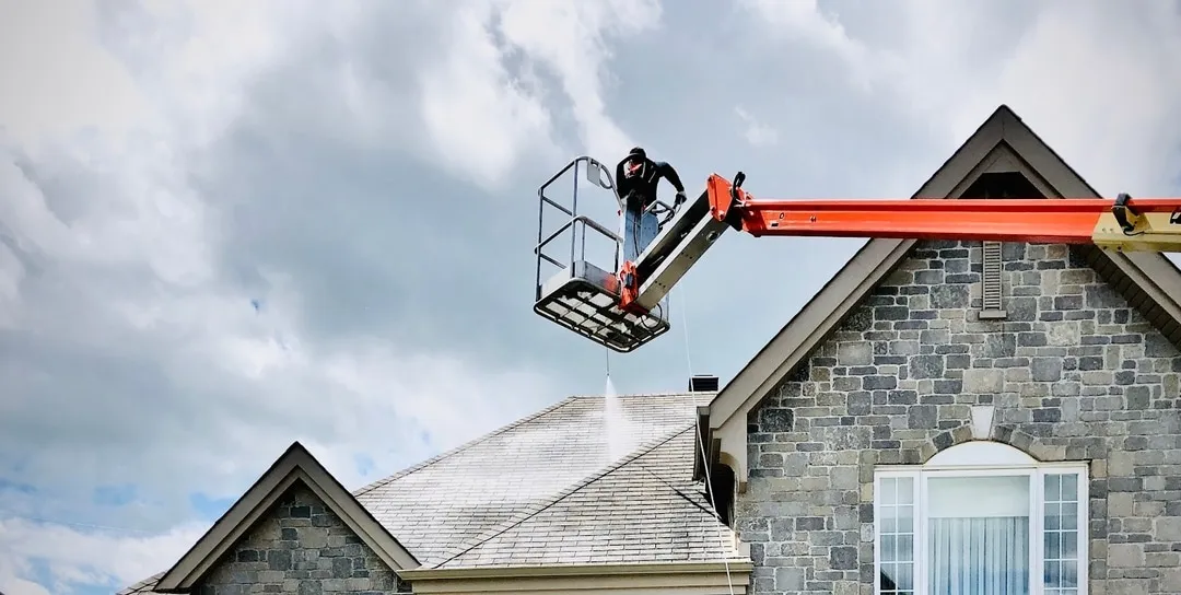 Residential roof being treated from a lift