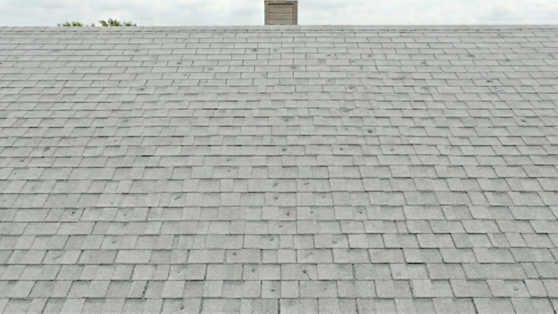 Asphalt shingle roof with visible hail damage indicators including granule loss and shingle discoloration.