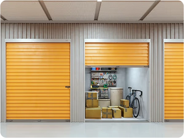Self-storage units with orange roll-up doors, one open showing boxes and a bicycle