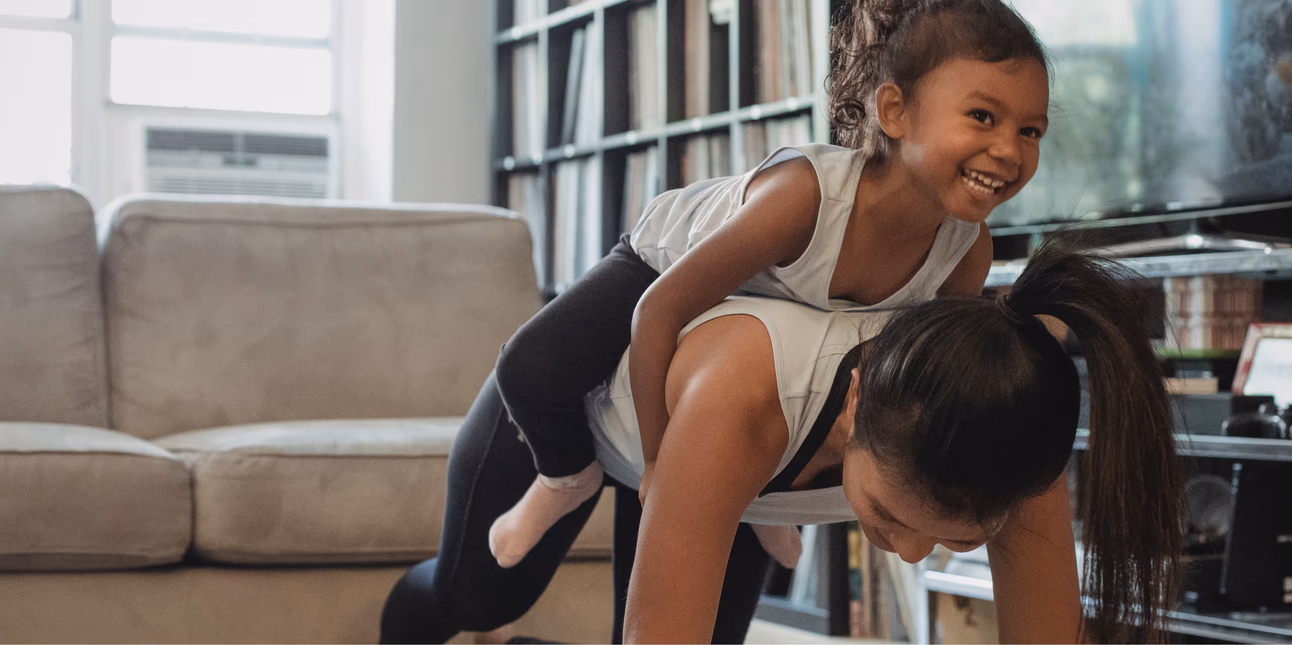 Mother and Daughter having fun together, daughter on Mother's back in a family room