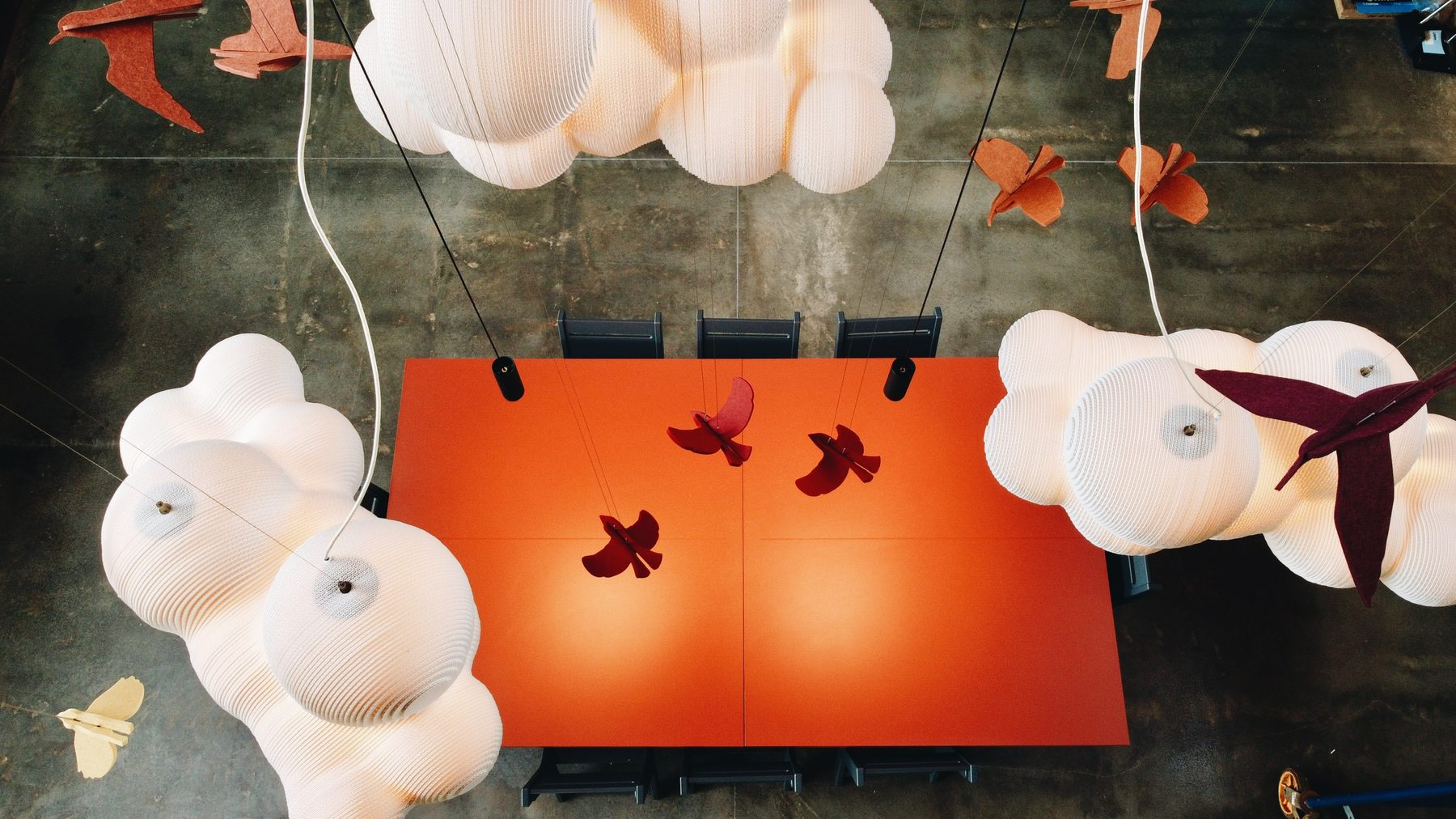 Looking down through cloud lights onto the orange dining table