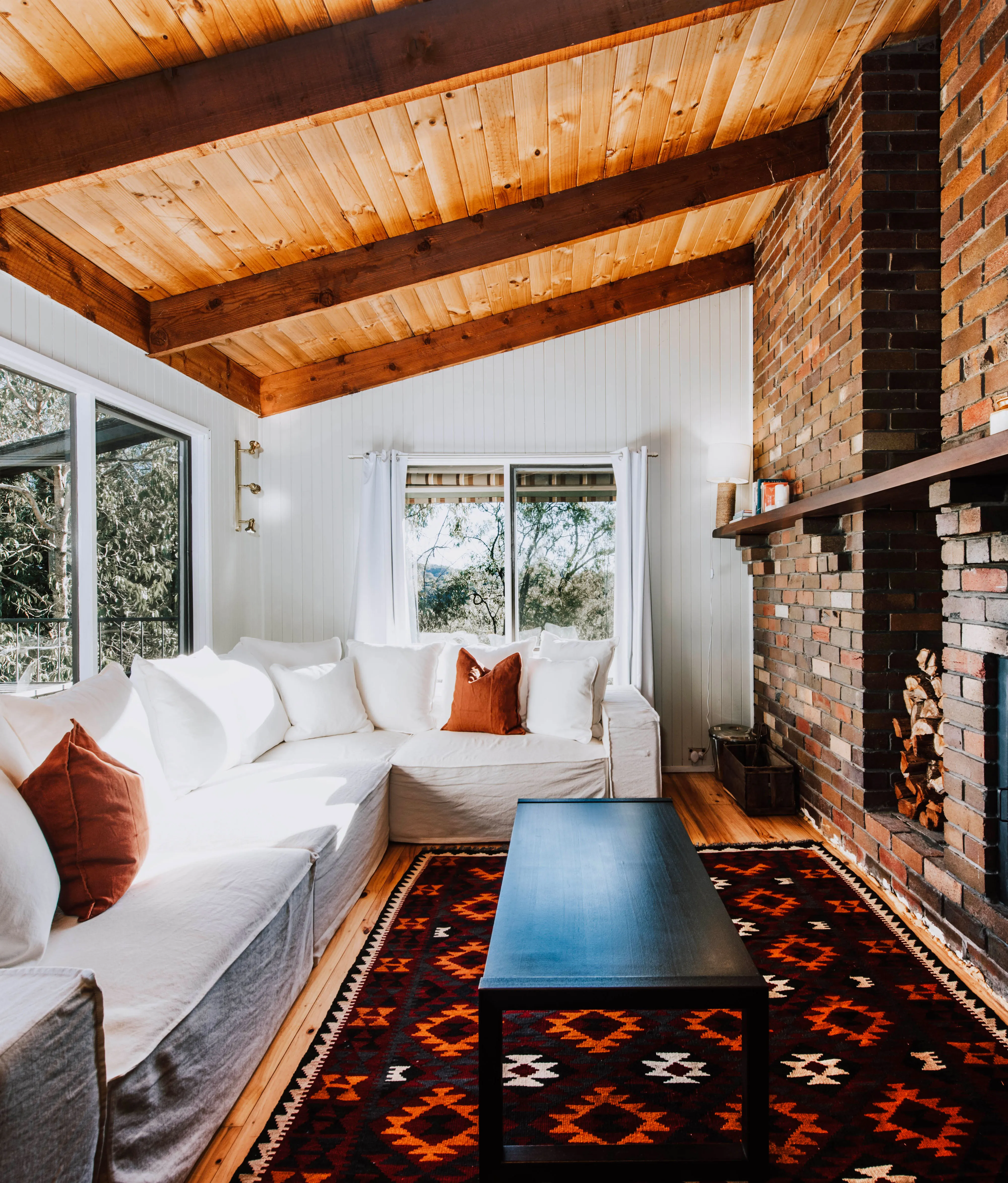 A white L-shaped couch in front of a black coffee table and a fireplace in the living room of Ilkley House: A Refreshing Family Rural Getaway, an Airbnb in Mudgee