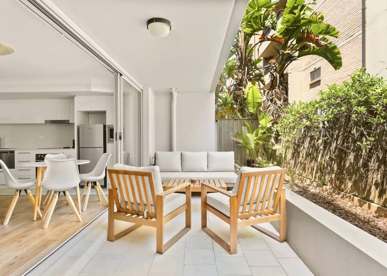 Outdoor patio with a round table, two wooden chairs, and a white couch
