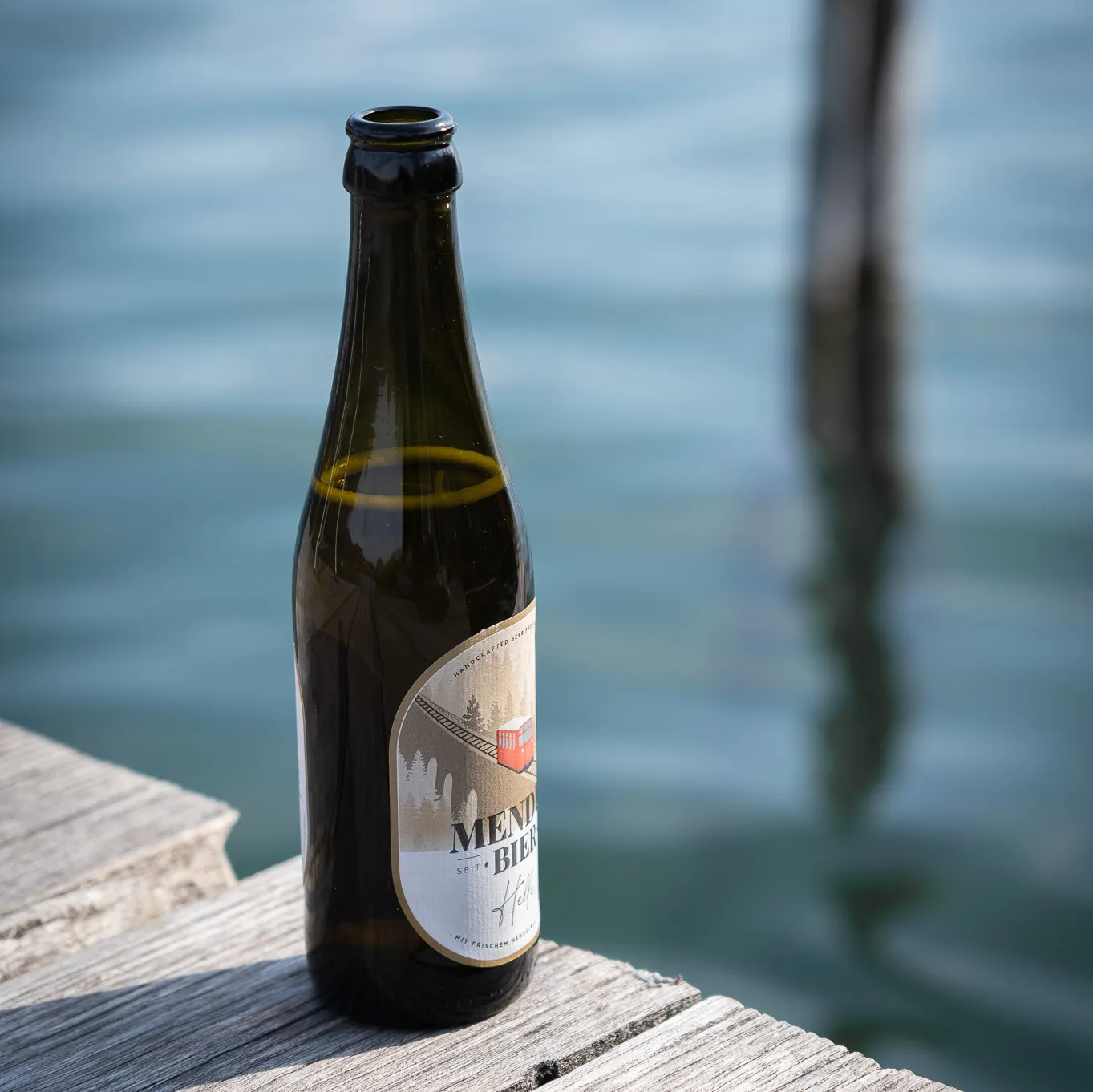 Flasche Mendelbier auf einem Holzsteg am Kalterer See