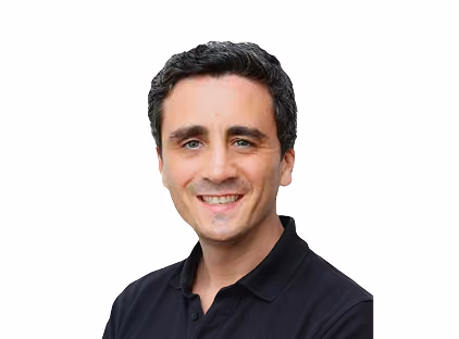 Smiling man with dark hair wearing a black collared shirt against a white background.
