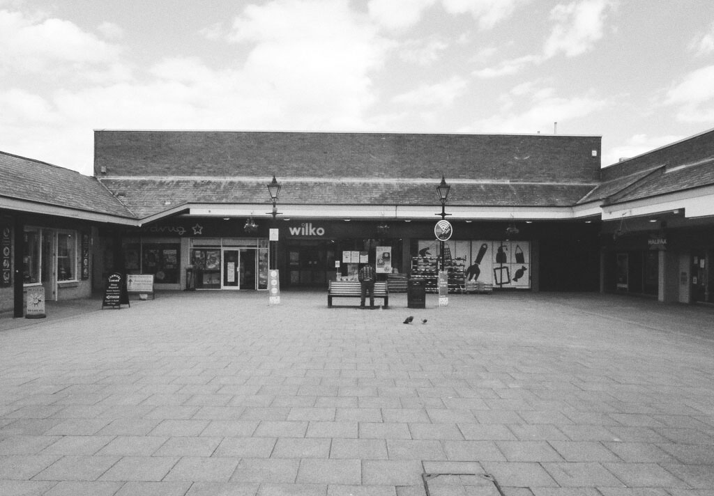 A black and white photo of Belvoir shopping area in Coalville, including a Wilko and Superdrug.