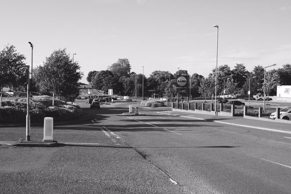 A black and white photo of the roundabout on Thornborough Road in Coalville, on the way to Swannington, with a sign for Lidl supermarket. 
