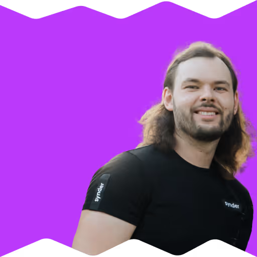 Smiling man with long hair and beard wearing a black Synder t-shirt.
