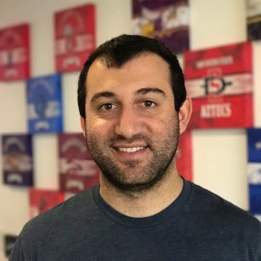 a man smiling in front of a wall of signs