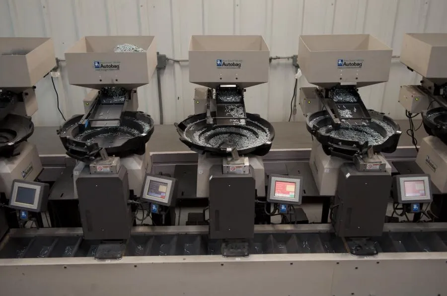 Row of automated bowl feeders processing metal fasteners