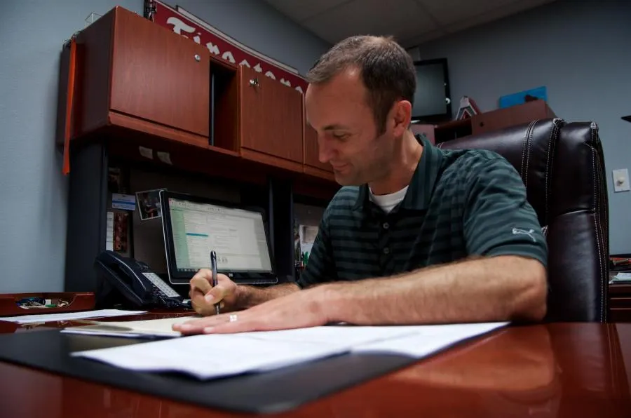 Nick reviewing paperwork at his desk