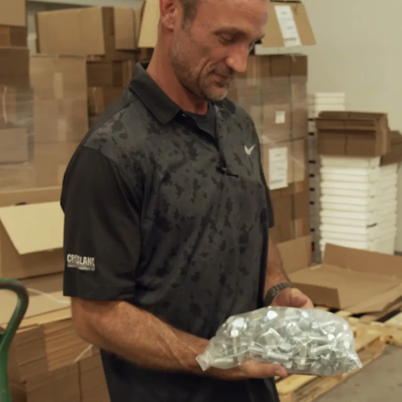Nick holding a bag of packaged metal fasteners in the Component Packaging warehouse
