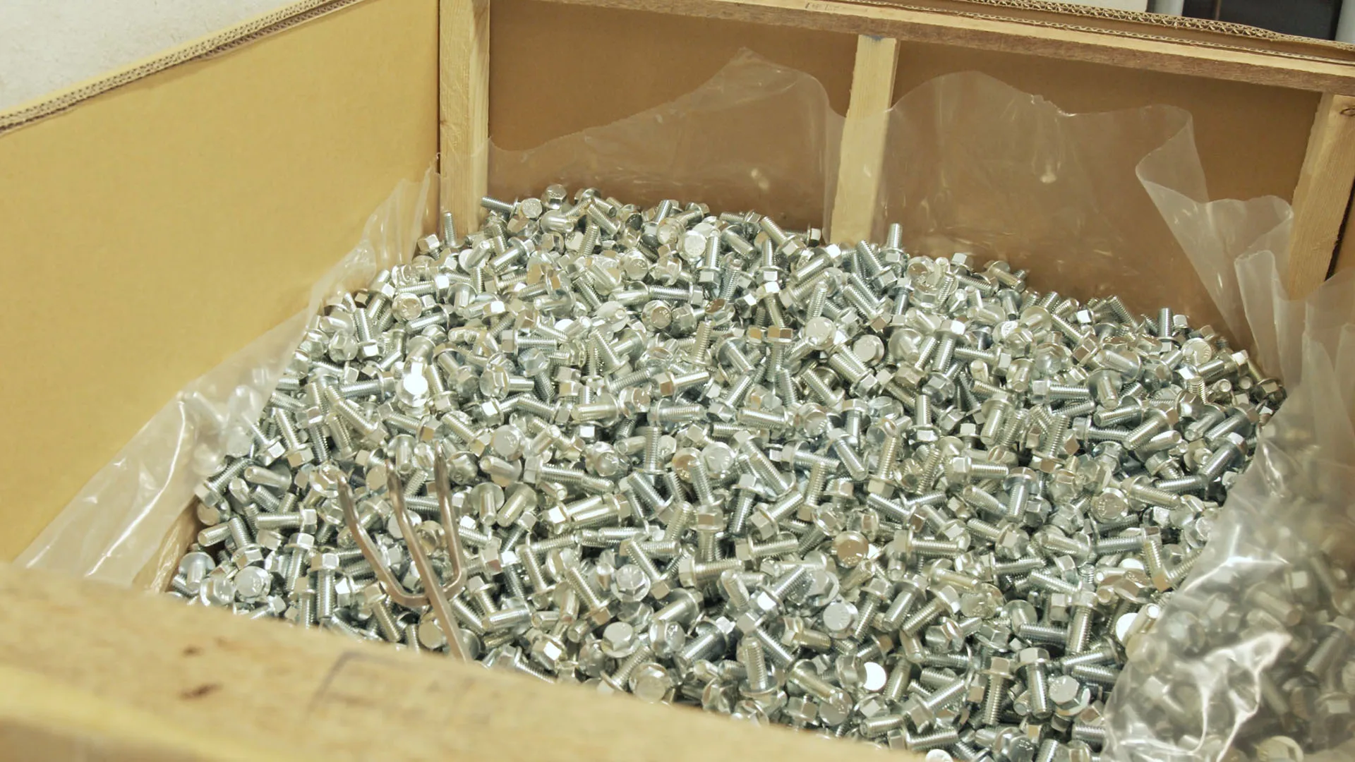 Large cardboard box filled with silver screws