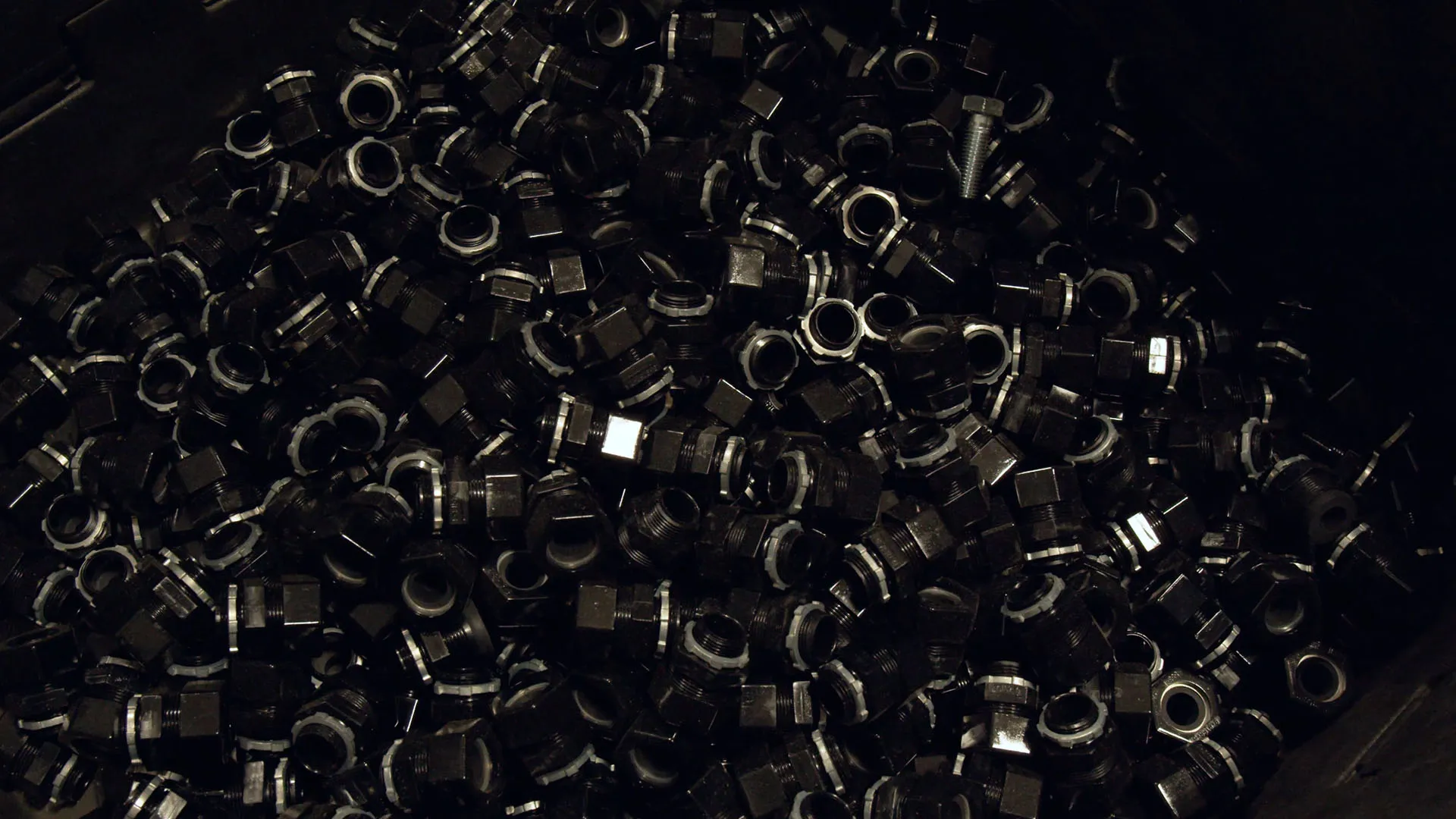 Close-up of dark steel nuts in a bulk container