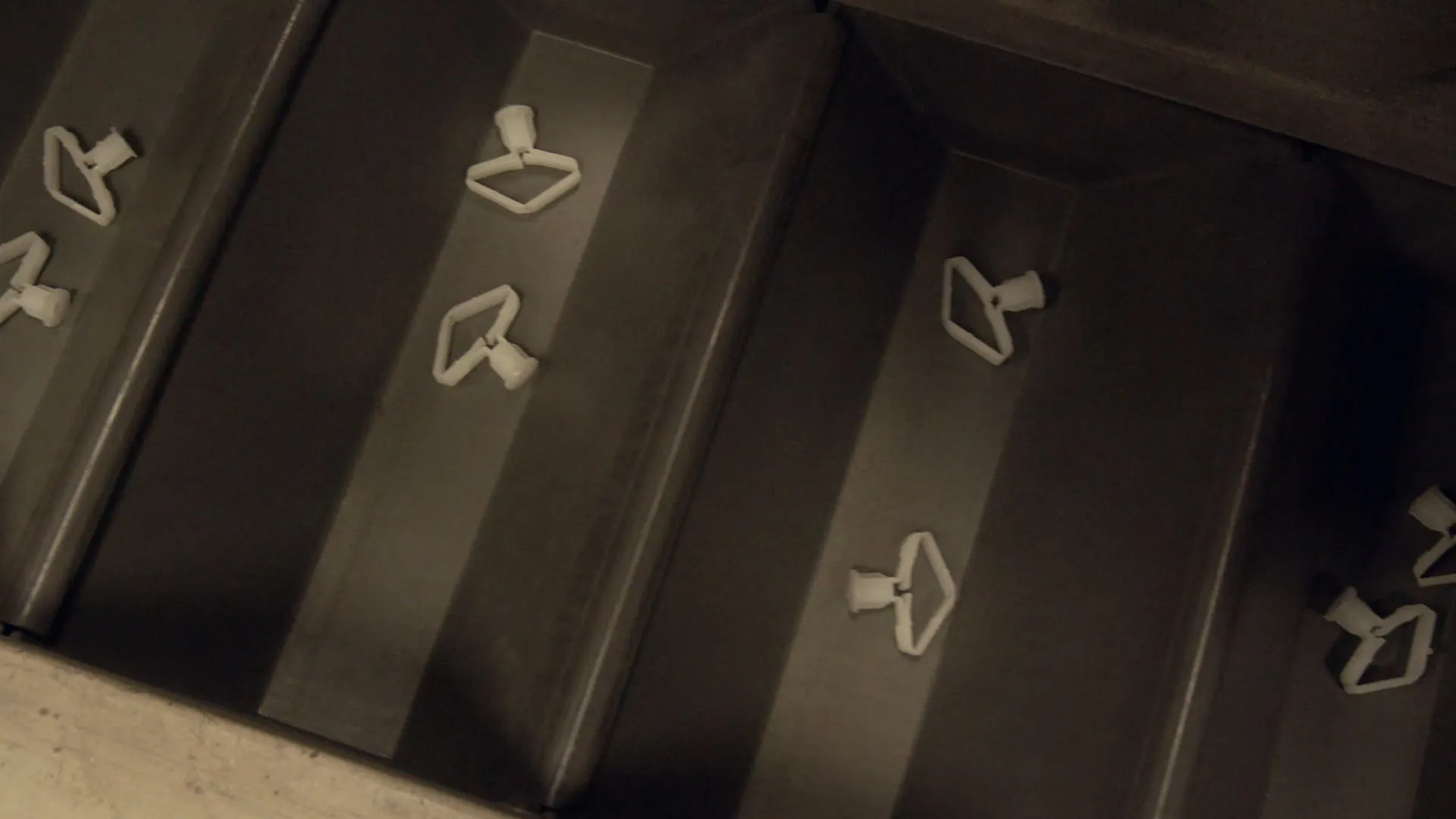 White plastic components moving along conveyor tracks